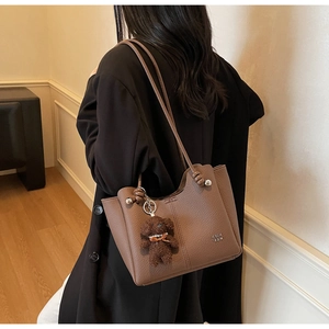 Dettaglio borsa tote in pelle martellata marrone scuro con ciondolo a forma di orso di peluche