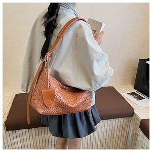 Detail of a brown woven hobo bag showing the intricate lattice craft and leather texture