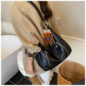 Close-up of black glossy tote bag with metal zipper and cute bear charm pendant