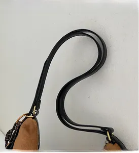 Close-up of brown suede handle with black edges and gold metal hardware detailing