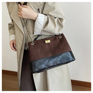 Detail of quilted diamond pattern and turn-lock closure on bicolor leather tote bag