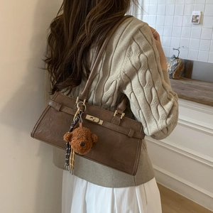 Detail view of deep brown vintage shoulder bag with plush bear charm and golden buckle