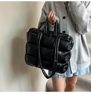 Detail of black quilted down tote bag with shiny nylon finish and dual carrying straps