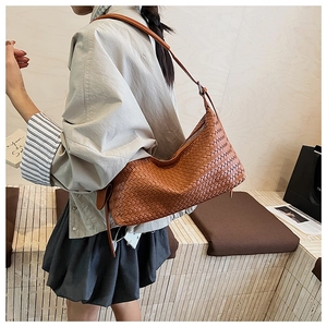 Close-up of brown woven leather hobo bag showing intricate Intrecciato texture and zip