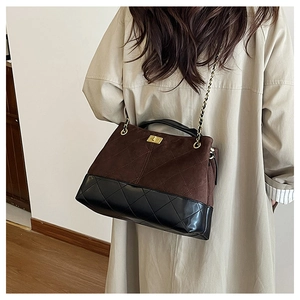 Detail of diamond quilted chain bag featuring contrast brown suede and black patent leather