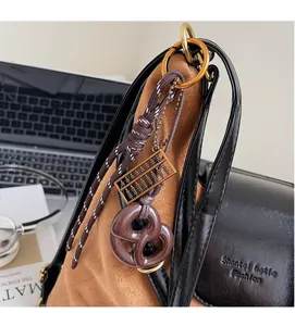 Detail of pretzel resin charm and mini golden abacus on a brown suede tote bag