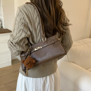 Detail of dark brown vintage faux leather shoulder bag with gold twist lock and bear charm