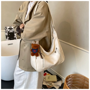 Detail of off-white faux leather tote bag with cute brown teddy bear charm accessory