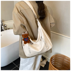 Detail of a large white Hobo bag in soft PU leather with brown bear charm detail