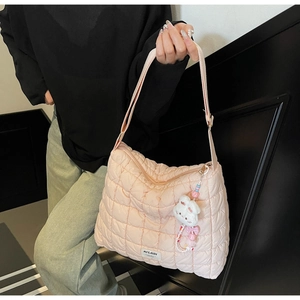 Detailed close-up of pink quilted puffer tote bag featuring a cute plush bear charm accessory