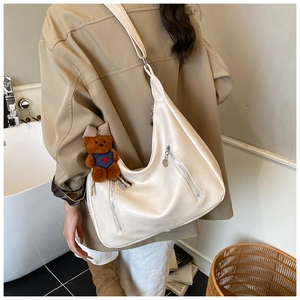 Detail of cream white PU leather tote bag with vertical zippers and bear charm decor
