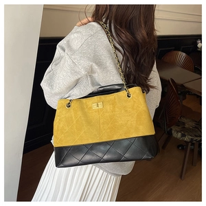 Close-up of yellow and black quilted shoulder bag with gold chain strap and turn-lock