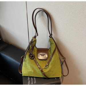 Detail of green suede hobo bag on a book showing vintage texture and leather strap