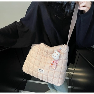 Detail of pink quilted puffer tote bag featuring a white label and cute rabbit doll charm