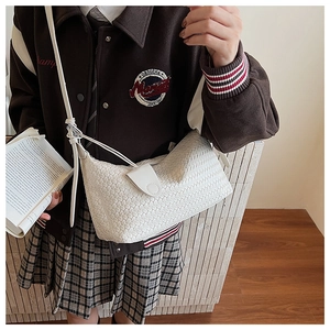 Close-up of white woven shoulder bag with gold buckle on a stylish female model