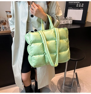 Close-up of light green quilted puffer tote bag with soft padded texture and top handles
