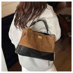 Close-up of diamond-quilted stitching on a dual-tone brown suede and black leather tote bag