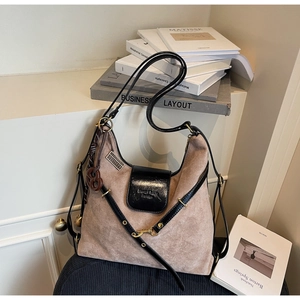 Detail of khaki suede hobo bag with black leather straps and decorative braided knot