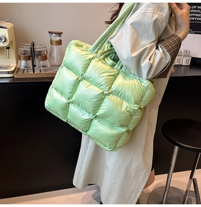 Quilted light green puffer tote bag shown on shoulder in a modern cafe setting