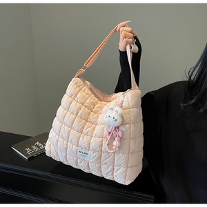 Detailed view of pink quilted tote bag with cute rabbit charm and logo patch detail