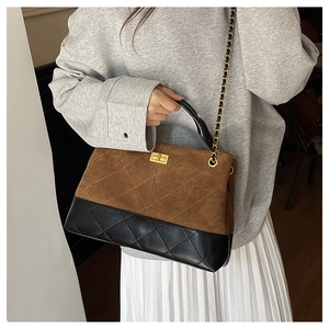 Quilted tote bag detail with brown suede and black leather patchwork and gold chain