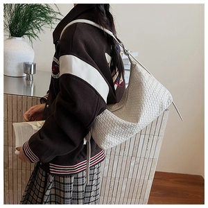 Detail of white large-grid woven leather hobo bag showing handmade texture and shoulder strap