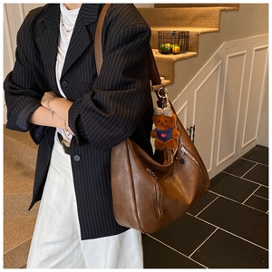 Retro dark brown leather tote bag with teddy bear charm shown on model in vintage interior