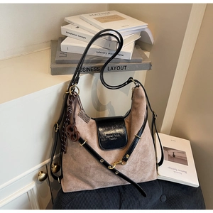 Detailed close-up of brown suede tote bag with black leather flap and gold metal accents