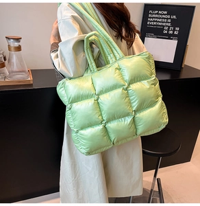 Close-up of quilted light green down puffer tote bag with glossy finish and soft texture