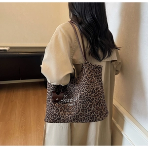 Detailansicht der Leopard-Tragetasche mit braunen Lederriemen und künstlerischem Text