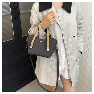 Detail view of woven grey bucket bag with brown handles on beige trench coat outfit