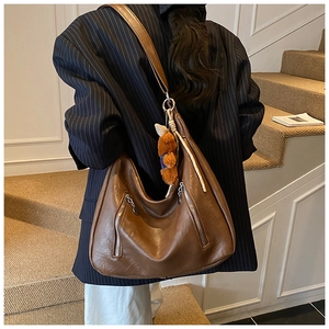 Detailed back view of vintage brown tote bag with bear charm on a model in a suit