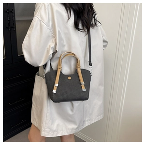 Detail of dark grey woven texture handbag with caramel leather handles and gold buckle