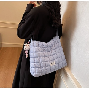 Detail of light blue quilted puffer tote bag with fluffy rabbit pendant and MULAIDI label