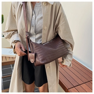 Macro view of dark brown woven leather texture and crossbody strap on a slouchy hobo bag