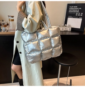 Close-up of silver quilted puffer tote bag featuring oversized square stitching detail