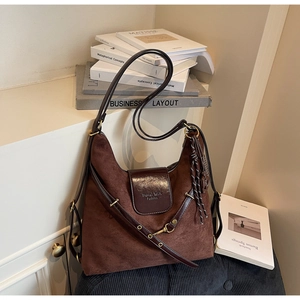 Detailed close-up of dark brown suede hobo bag with leather flap and tassel detail