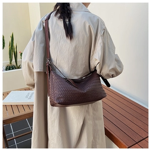 Macro detail of dark brown woven leather hobo bag with adjustable strap on beige coat