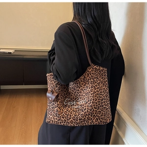 Detail der Leopard-Tasche mit weißem Textdruck und braunem Kunstledergriff im Fokus