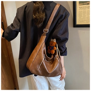 Brown faux leather tote bag with vertical zippers and bear charm shown on a model