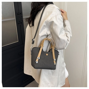 Detail of a charcoal woven bucket bag with brown leather handle and silver metal hardware