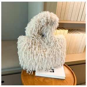 Gros plan d'un sac cabas en fausse fourrure blanc cassé sur une table en bois avec livres
