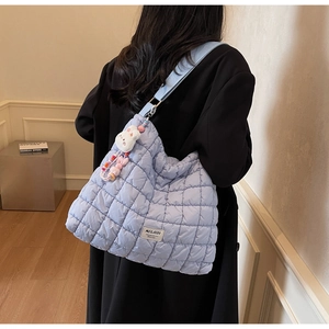 Detail of light blue quilted tote bag with cute plush rabbit pendant and brand label