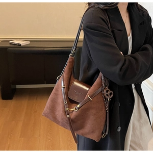 Detail of dark brown suede tote bag featuring a leather flap and woven knot pendant
