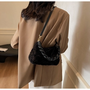 Détail du sac bandoulière noir en fausse fourrure avec poignée chaîne tressée sur modèle