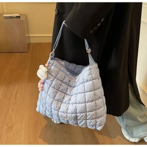 Detail of light blue quilted tote bag with soft puffer texture and cute rabbit charm