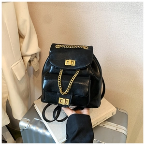 Detailansicht eines schwarzen Leder-Rucksacks mit goldener Kette und Metalldrehverschlüssen