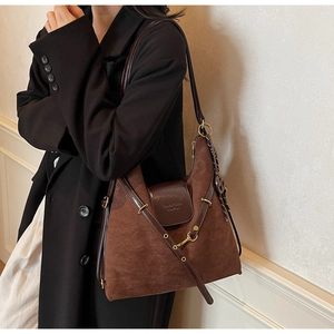 Brown suede tote bag with leather straps shown on a model in a minimalist setting
