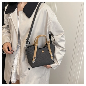 Detail of dark grey woven crossbody bucket bag with tan leather straps on model