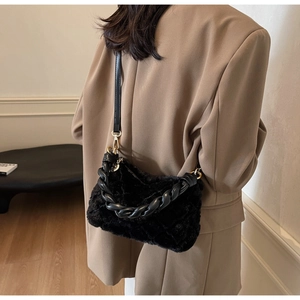 Détail d'un sac bandoulière en fausse fourrure noire avec chaîne et ferrures dorées
